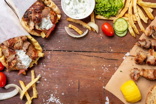 Gyro pita, shawarma, souvlaki. Dois embrulhos de pão pita e espetos de carne na mesa de madeira — Fotografia de Stock