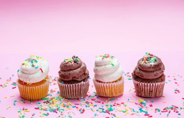 Pembe arka plan, kopya alanı üzerinde renkli sprinkles ile cupcakes.