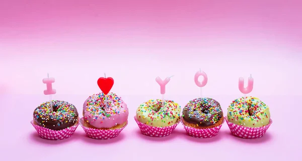 Mini ciastka z oblodzeniem i kolorowe kropi na różowym tle, tekst, kocham Cię — Zdjęcie stockowe