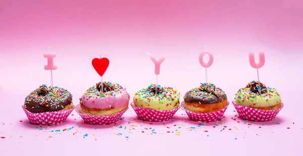 Mini kek ile krema ve renkli şeker pembe arka plan, metin seni seviyorum — Stok fotoğraf