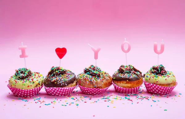 Mini-Kuchen mit Zuckerguss und bunte Streusel auf rosa Hintergrund, Text ich liebe dich — Stockfoto