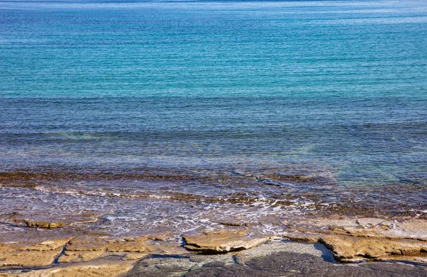 Blå lugna turkosa havet vatten, klippiga stranden textur bakgrund — Stockfoto