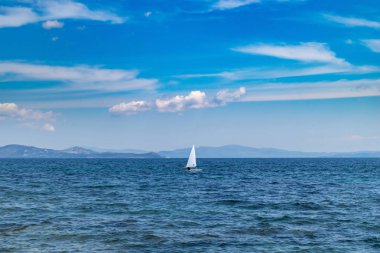 Beyaz yelken, mavi gökyüzü ve deniz arka plan ile küçük iyimser tekne