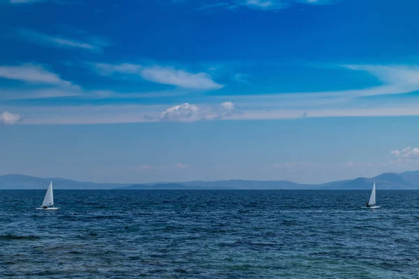 Kis optimista hajók fehér vitorlák, kék ég és a tenger háttér — Stock Fotó