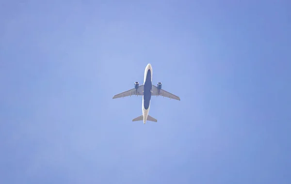 White and blue color commercial airplane against clear sky background. view from below — ストック写真