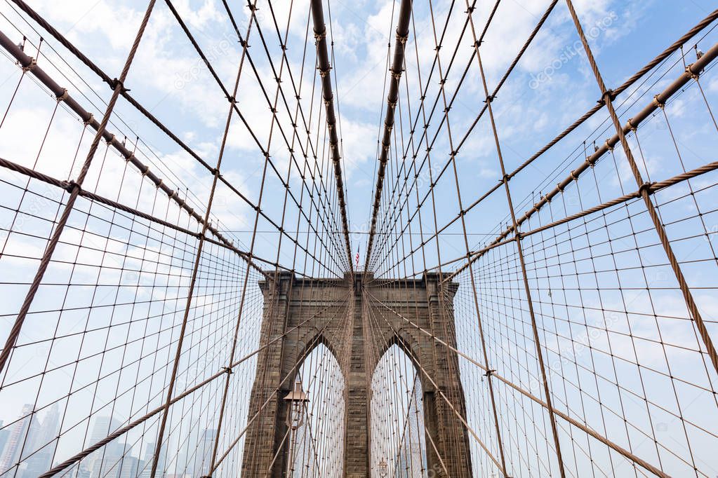 Brooklyn Bridge detail against blue cloudy sky background. New York city, Manhattan
