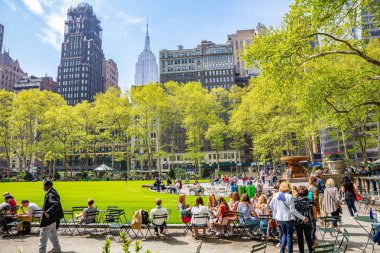 Bryant Parkı, New York, Manhattan. İnsanlar rahatlatıcı, ilkbaharda güneşli bir gün