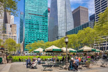 Bryant Parkı, New York, Manhattan. İnsanlar rahatlatıcı, ilkbaharda güneşli bir gün