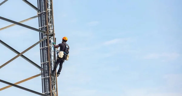 Manutenção de telecomunicações. Trabalhador escalador na torre contra o fundo do céu azul — Fotografia de Stock