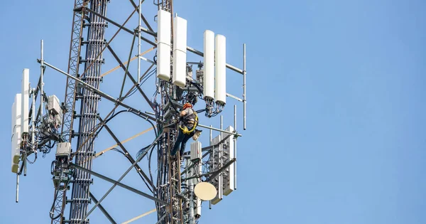 Техническое обслуживание. Человек альпинист на башне на фоне голубого неба — стоковое фото