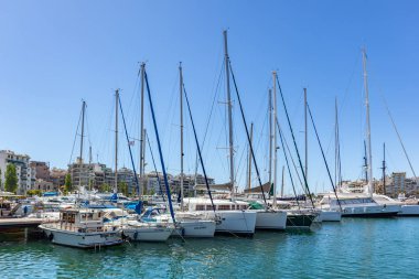 Marina Zeas Pire, Yunanistan. Birçok demirli gemi. Teknelerin yansıması, mavi sakin deniz, şehir ve gökyüzü arka plan.