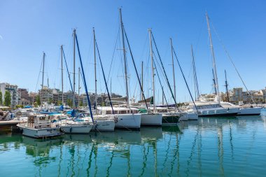 Marina Zeas Pire, Yunanistan. Birçok demirli yat. Teknelerin yansıması, mavi sakin deniz, şehir ve gökyüzü arka plan.