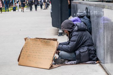 Karton tabelalı evsiz adam, şehir merkezinde yalvarıyor.