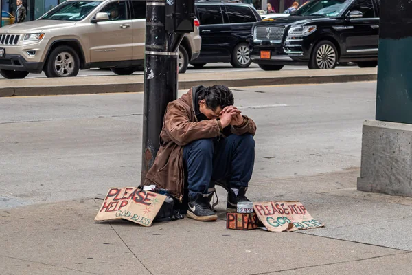 Бездомный, сидящий на обочине дороги и просящий помощи, в центре города — стоковое фото