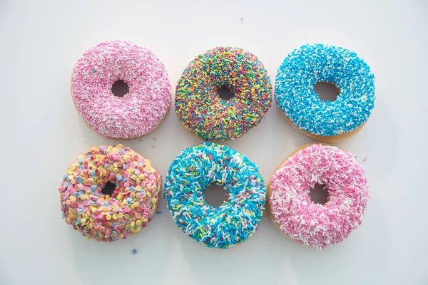 Doughnuts with colorful decoration on white color background. Top view — Stock Photo, Image