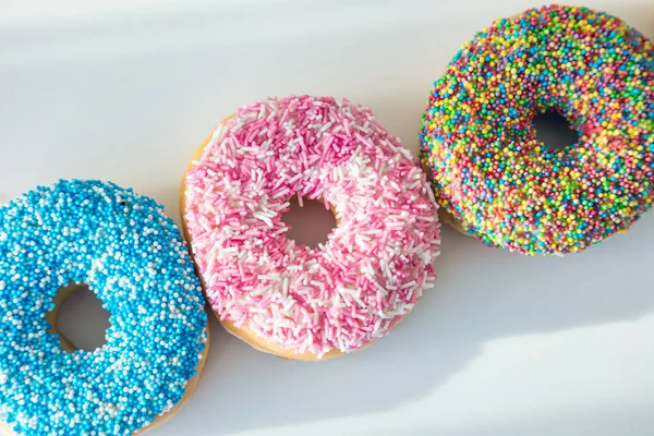 Rosquillas con decoración colorida sobre fondo de color blanco. Vista superior — Foto de Stock