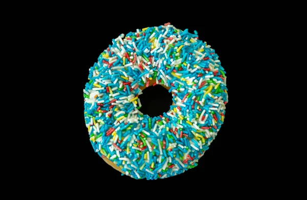 Doughnut with blue sprinkles isolated on black color background. Top view — Stock Photo, Image