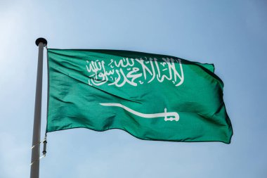 Açık mavi gökyüzüne el sallayan Suudi Arabistan bayrağı