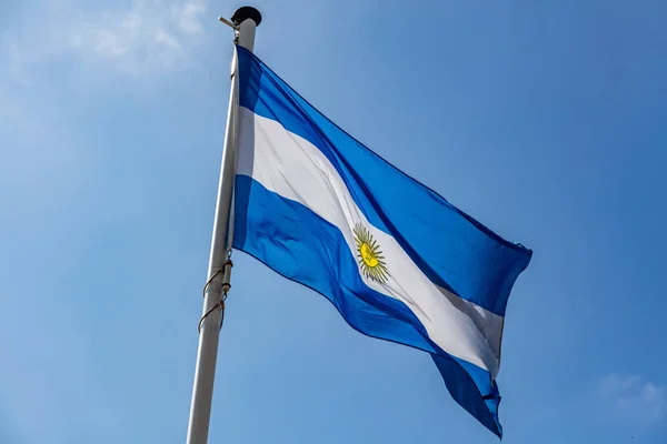 Arjantin bayrağı sallayarak karşı açık mavi gökyüzü — Stok fotoğraf