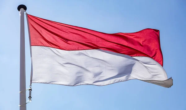 Bendera Indonesia melambai melawan langit biru yang cerah — Stok Foto