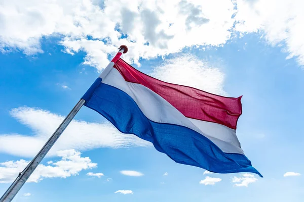 Флаг Голландии, размахивающий голубым небом с облаками — стоковое фото