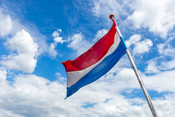 Holland Flag viftande mot blå himmel med moln — Stockfoto