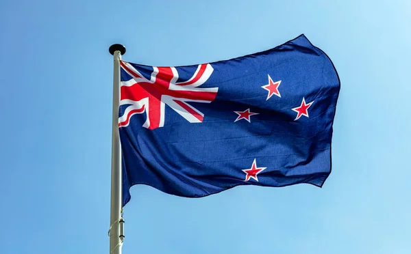 Bandera de Nueva Zelanda ondeando contra el cielo azul claro —  Fotos de Stock