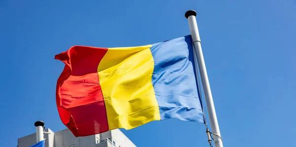 澄んだ青空に向かうルーマニアの旗 — ストック写真