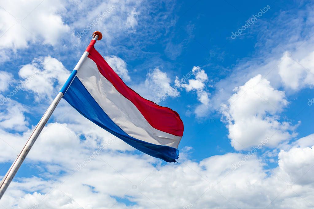 Holland flag waving against blue sky with clouds