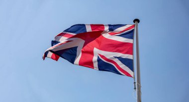 Büyük Britanya bayrağı açık mavi gökyüzüne karşı sallayarak