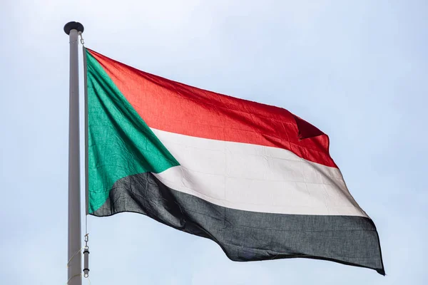 Bandera de Sudán ondeando contra el cielo azul claro — Foto de Stock