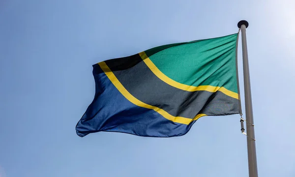 Tanzanias flagga vifta mot klarblå himmel — Stockfoto