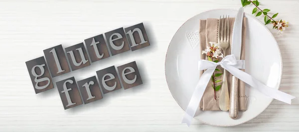 Gluten-free text and cutlery on a plate, white wood background, 3d illustration