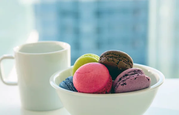 Bunte Macarons und Kaffeetasse auf weißem Hintergrund, Nahsicht — Stockfoto