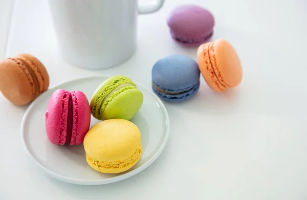 Macarons colorés et tasse à café sur fond blanc, vue rapprochée — Photo