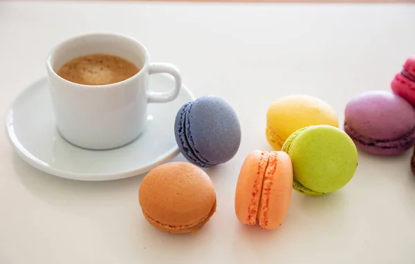 Macarons colorés et tasse à café sur fond blanc, vue rapprochée — Photo