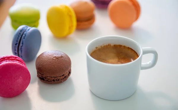 Bunte Macarons und Kaffeetasse auf weißem Hintergrund, Nahsicht — Stockfoto