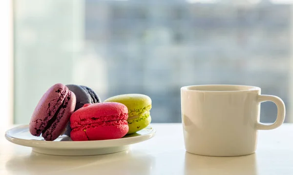 Bunte Macarons und Kaffeetasse auf weißem Hintergrund, Nahsicht — Stockfoto