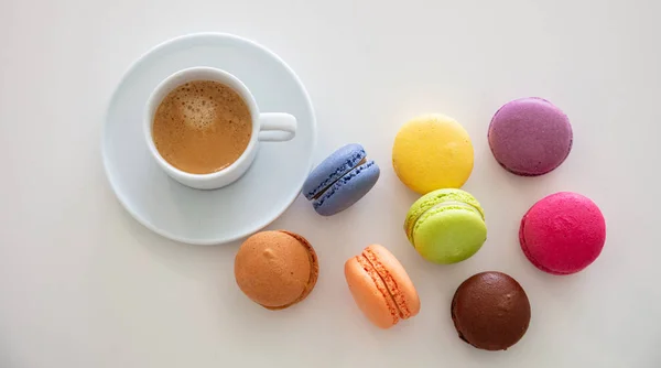 Colorful macarons and coffee cup on white background, close up view — Stock Photo, Image