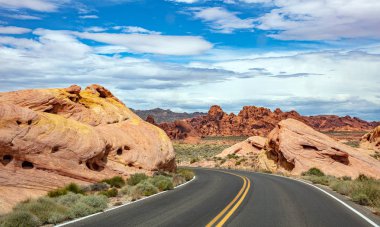 Iniş ve iniş, bulutlu mavi gökyüzü ile uzun dolambaçlı karayolu. Valley of Fire Nevada, Amerika Birleşik Devletleri