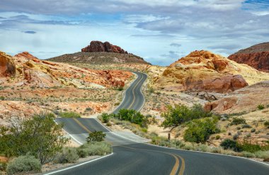 Iniş ve iniş, bulutlu mavi gökyüzü ile uzun dolambaçlı karayolu. Valley of Fire Nevada, Amerika Birleşik Devletleri