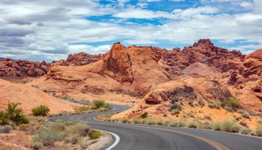 Iniş ve iniş, bulutlu mavi gökyüzü ile uzun dolambaçlı karayolu. Valley of Fire Nevada, Amerika Birleşik Devletleri
