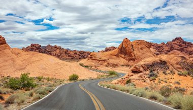 Iniş ve iniş, bulutlu mavi gökyüzü ile uzun dolambaçlı karayolu. Valley of Fire Nevada, Amerika Birleşik Devletleri