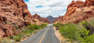 Iniş ve iniş, bulutlu mavi gökyüzü ile uzun dolambaçlı karayolu. Valley of Fire Nevada, Amerika Birleşik Devletleri