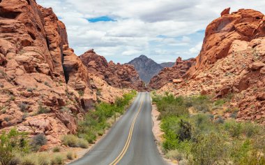 Iniş ve iniş, bulutlu mavi gökyüzü ile uzun dolambaçlı karayolu. Valley of Fire Nevada, Amerika Birleşik Devletleri