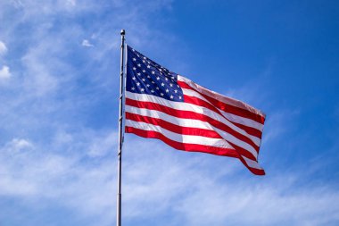 Mavi gökyüzü arka planda sallayarak bir kutup üzerinde Amerika Birleşik Devletleri bayrağı.