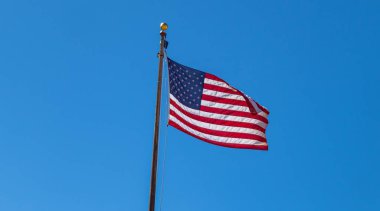 Mavi gökyüzü arka planda sallayarak bir kutup üzerinde Amerika Birleşik Devletleri bayrağı.