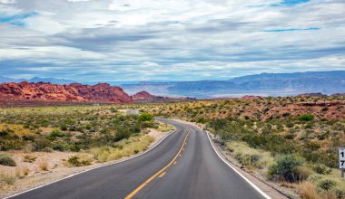 Iniş ve iniş, bulutlu mavi gökyüzü ile uzun dolambaçlı karayolu. Valley of Fire Nevada, Amerika Birleşik Devletleri