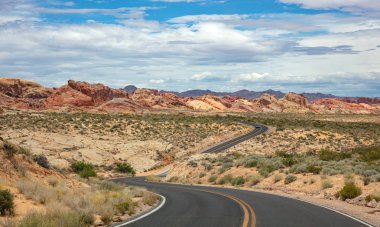Iniş ve iniş, bulutlu mavi gökyüzü ile uzun dolambaçlı karayolu. Valley of Fire Nevada, Amerika Birleşik Devletleri