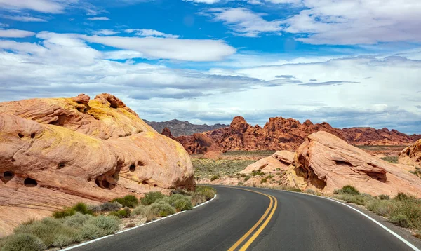 Iniş ve iniş, bulutlu mavi gökyüzü ile uzun dolambaçlı karayolu. Valley of Fire Nevada, Amerika Birleşik Devletleri
